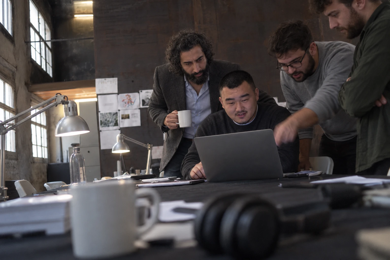 The project manager, the lead engineer and colleagues gathered round a laptop at a desk in the studio.